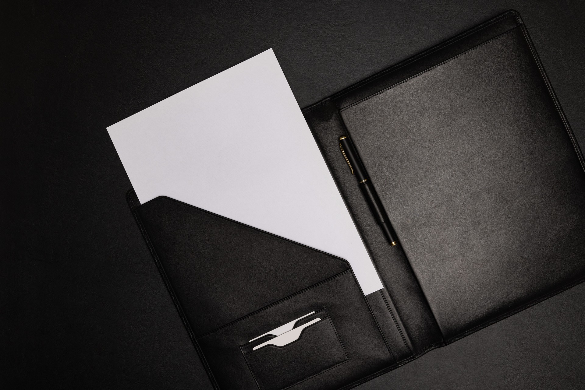 Dossier en cuir noir avec feuille de papier blanc vierge